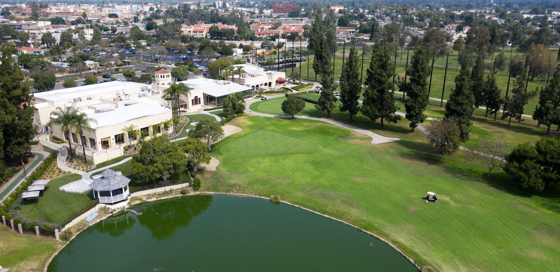 Aerial view of golf course, clubhouse, and pond